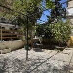 Αυλή πολυκατοικίας με δέντρα και μεταλλική πέργκολα