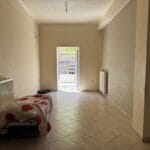 Άδειο δωμάτιο με μονό στρώμα και ανοιχτή πόρτα