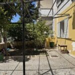 Μικρή αυλή με κίτρινο κτίριο και δέντρα