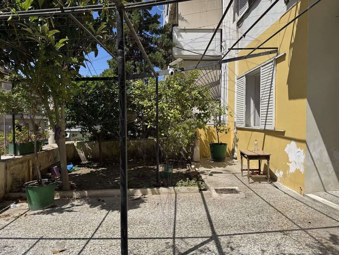 Μικρή αυλή με κίτρινο κτίριο και δέντρα
