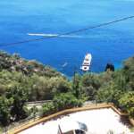 Θέα θάλασσας με γιοτ και καταπράσινο λόφο