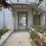 Είσοδος παλιού λευκού σπιτιού με μικρό κήπο