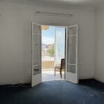 Άδειο δωμάτιο με ανοιχτές μπαλκονόπορτες και θέα πόλης