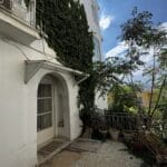 Είσοδος λευκής κατοικίας με κισσό και μπαλκόνι