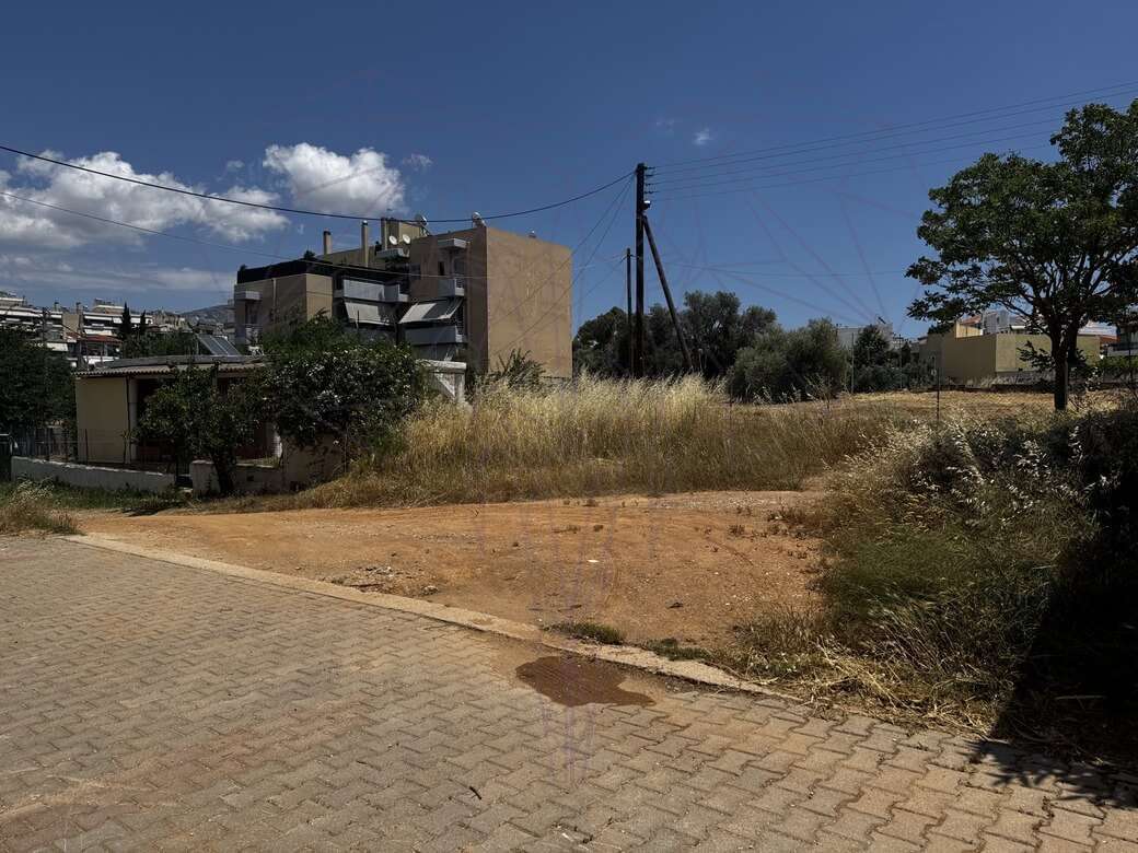 Άδειο οικόπεδο με ξερά χόρτα σε γειτονιά