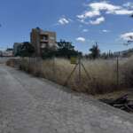 Πεζοδρόμιο δίπλα σε περιφραγμένο οικόπεδο με ξερά χόρτα