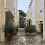 Στενό βρεγμένο αίθριο ανάμεσα σε κτίρια με γλάστρες