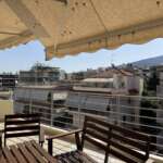 Ηλιόλουστο μπαλκόνι με θέα σε πολυκατοικίες και λόφο